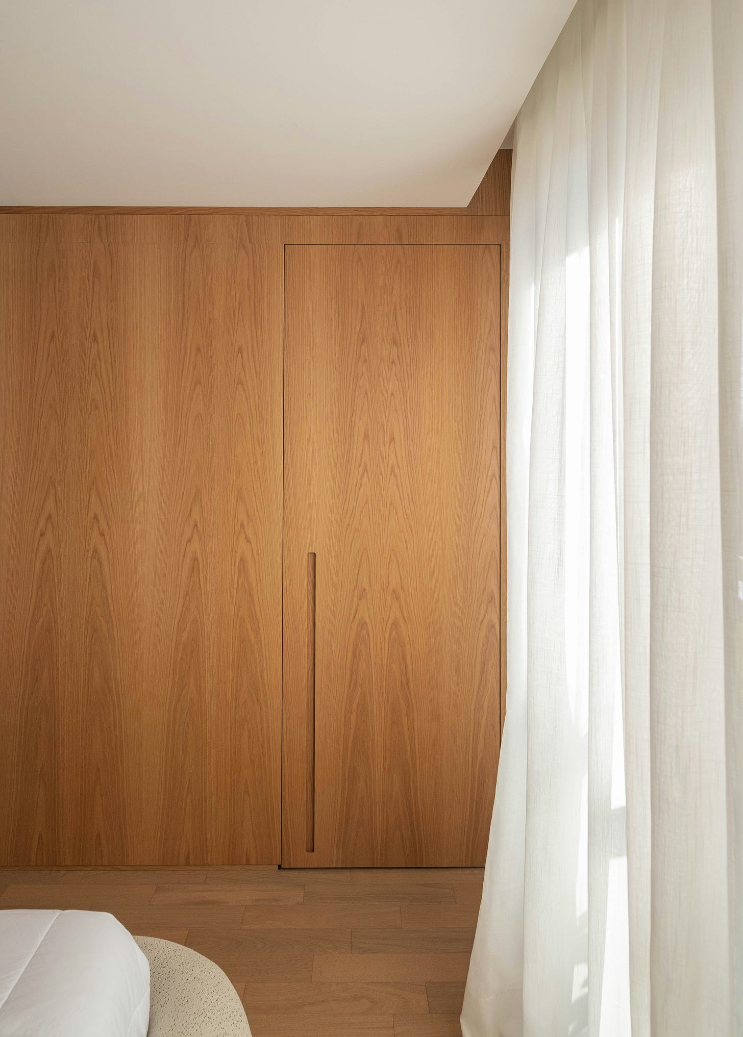 Sheer linen drapery filtering daylight beside warm wood paneling in a quiet, minimalist interior. Sheer linen drapery filtering daylight beside warm wood paneling in a quiet, minimalist interior.