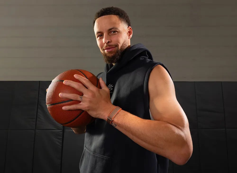 Stephen Curry holding a basketball while wearing the Stephen Curry Fitbit Air Special Edition.