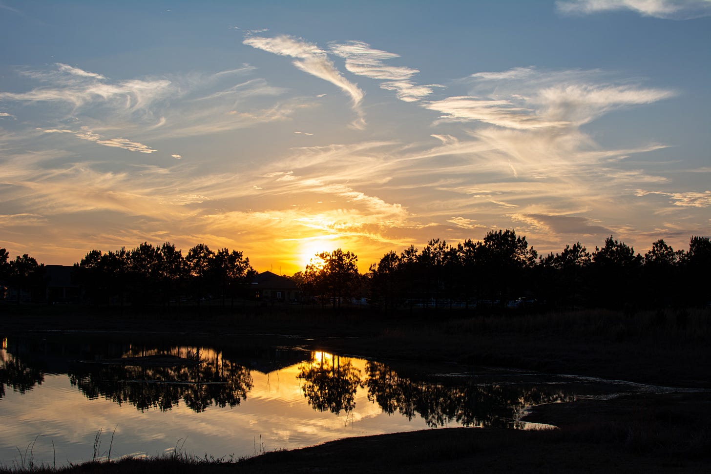 the sun sets over a lake and trees with their reflections in the lake water