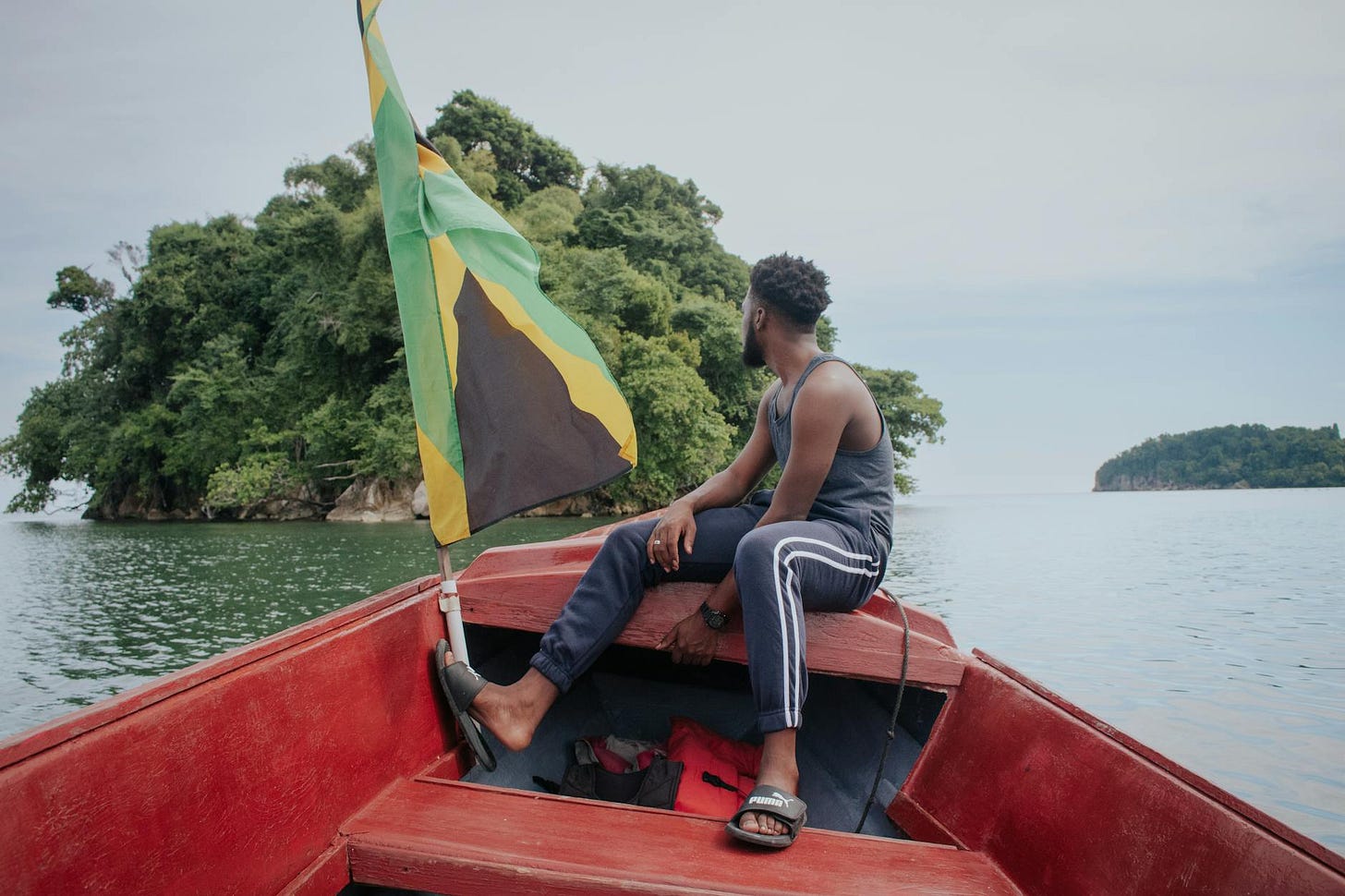 man sitting on boat with jamaican flag
