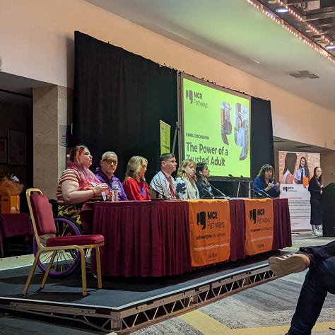 photo 1: A promotional MCR Pathways graphic with text on the left about embracing the future, and a photograph on the right showing a person seated in a wheelchair, wearing a patterned jacket and smiling.  photo 2: A panel of speakers seated on a stage at the MCR Pathways Summit, with a large screen behind them displaying the title “The Power of a Trusted Adult.” The panel sits behind tables covered in MCR Pathways branding.  photo 3: A person with brightly coloured hair and bold makeup sitting at a round table during the Summit, wearing a rainbow striped top and a badge-covered lanyard, listening attentively with a soft smile.  photo 4: A close-up selfie taken indoors. The person has bright multicoloured eye makeup and long multicoloured hair, wearing a rainbow striped top and a lanyard decorated with character badges.  photo 5: A mirror selfie in an accessible bathroom. The person is seated in a wheelchair, wearing sunflower-patterned trousers and a rainbow striped top, smiling while holding their phone.  photo 6: A page of printed panel questions for the Summit, presented in a clean bullet-point list covering topics such as mentoring, trusted adults, social impact, and programme development.