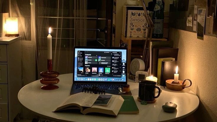 This may contain: an open laptop computer sitting on top of a table next to a book and candle