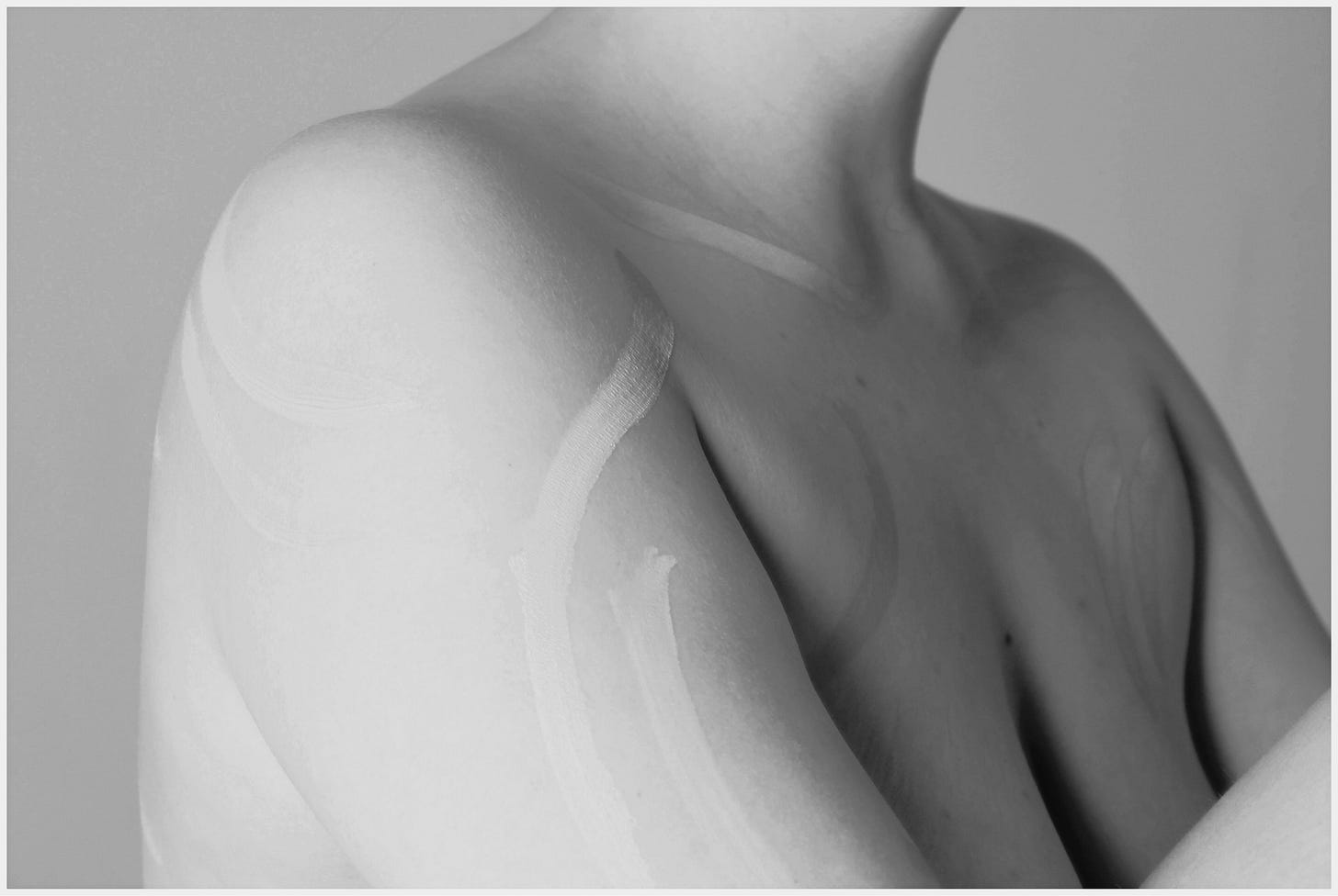 A black & white image of a woman's naked upper-body, adorned with lines of paint.