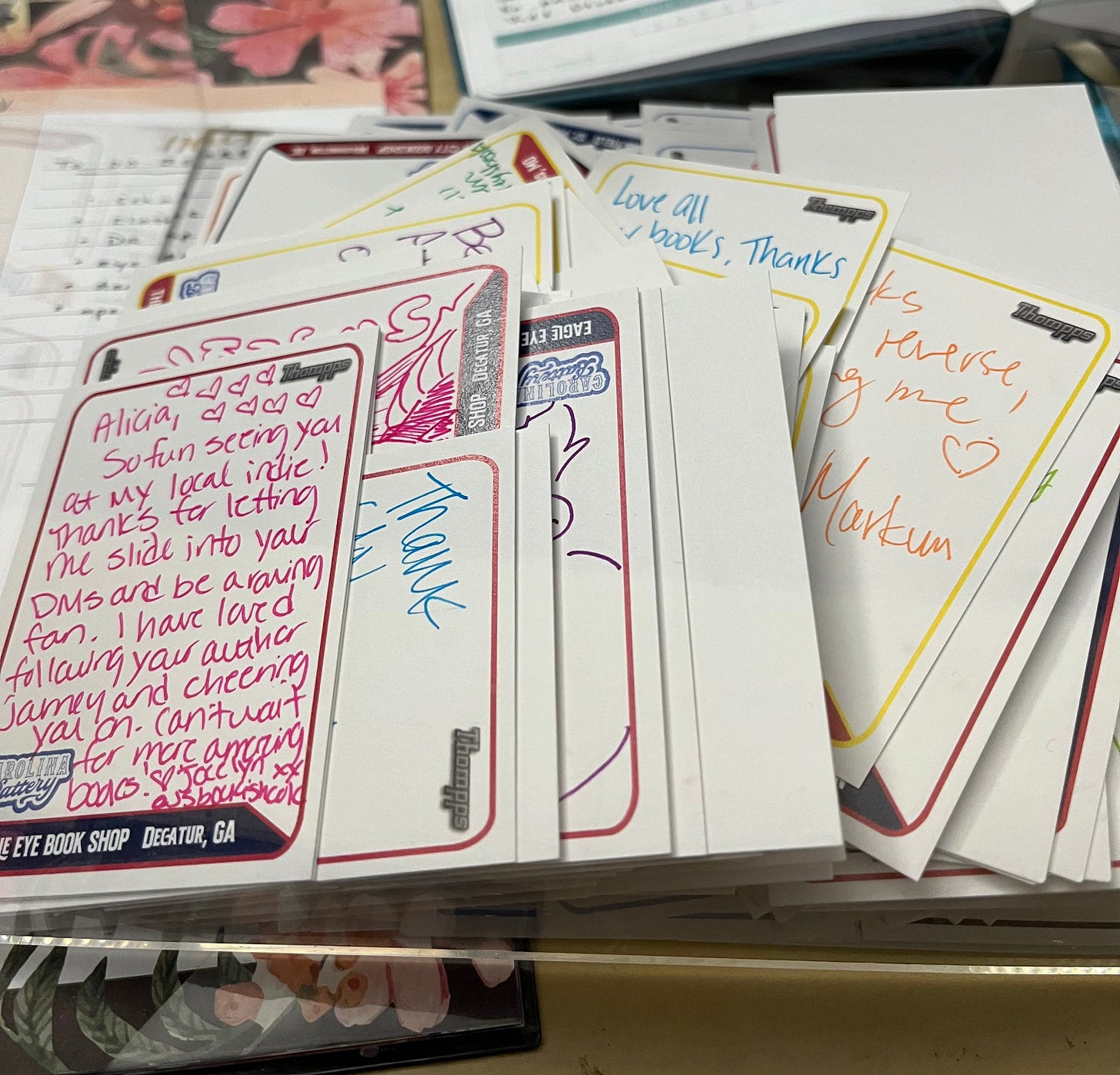 A pile of signed blank baseball cards with handwritten mesages on them in different colored pens