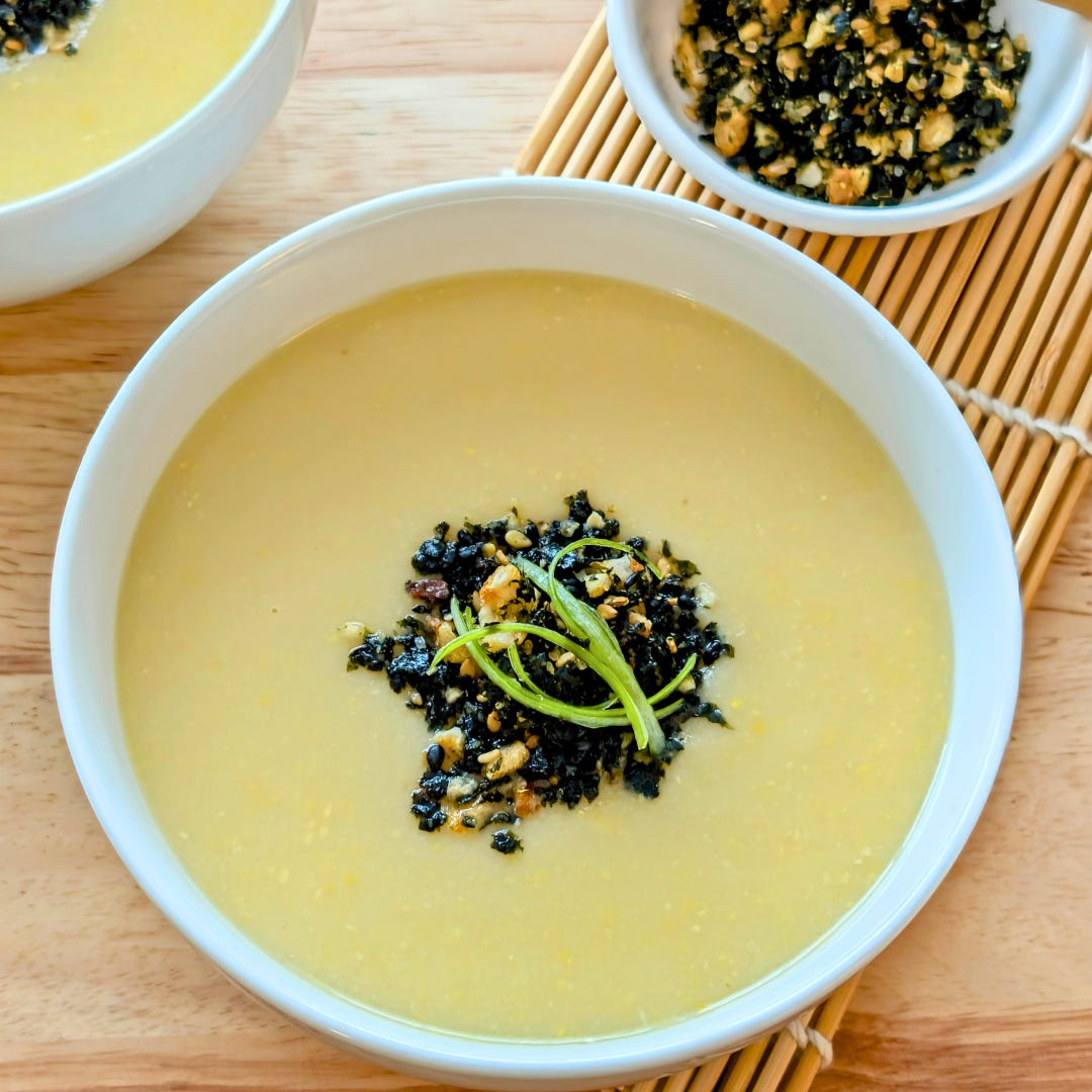 A bowl of plant-based Japanese corn potage topped with corn furikake, served with a small side bowl of extra furikake.