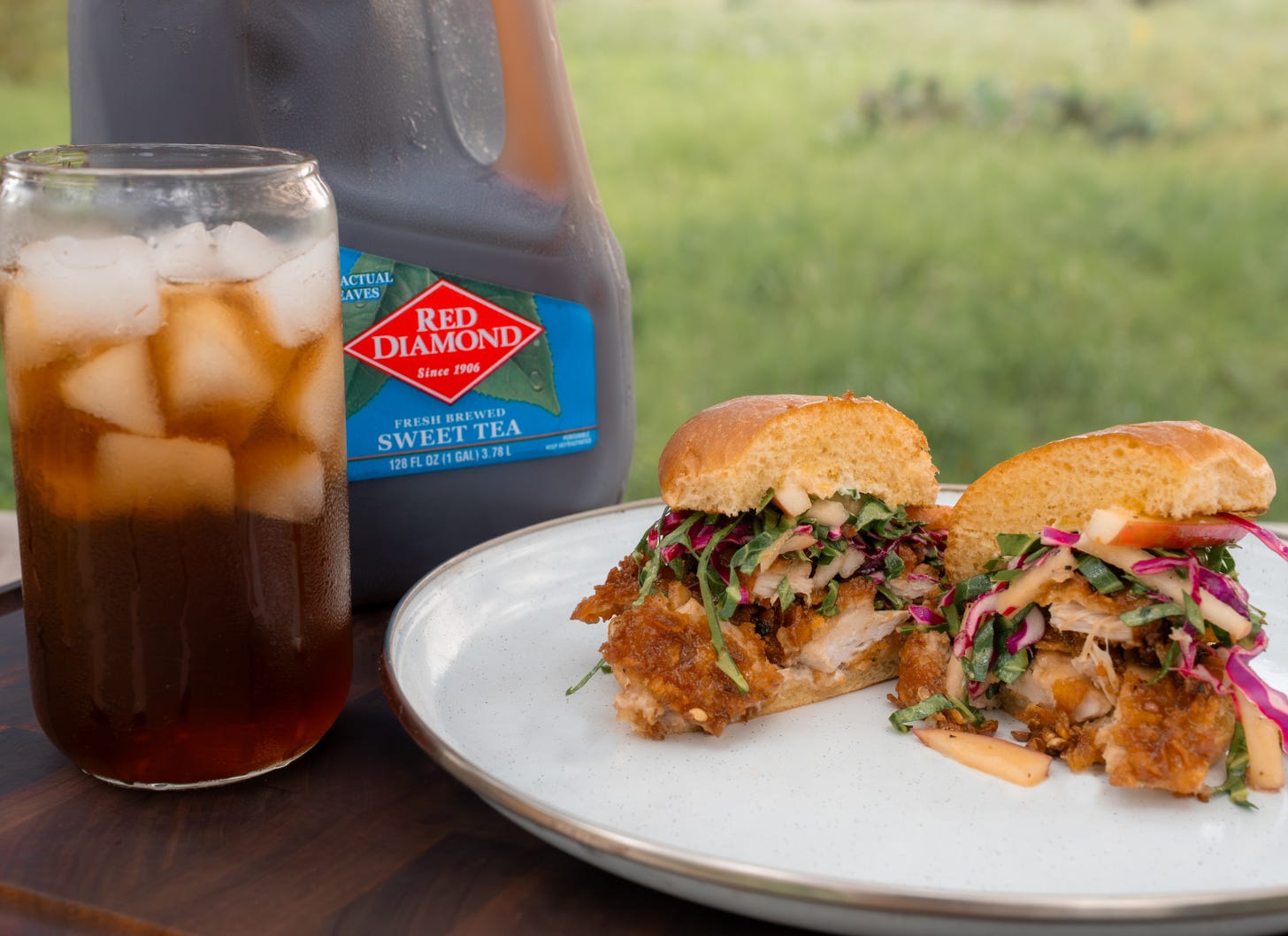 A Sweet Tea Fried Wild Turkey Sandwich with apple-collard slaw and Szechuan glaze, created by Josh Crumpton for Red Diamond Tea, served outdoors with a glass of iced sweet tea. A Sweet Tea Fried Wild Turkey Sandwich with apple-collard slaw and Szechuan glaze, created by Josh Crumpton for Red Diamond Tea, served outdoors with a glass of iced sweet tea.