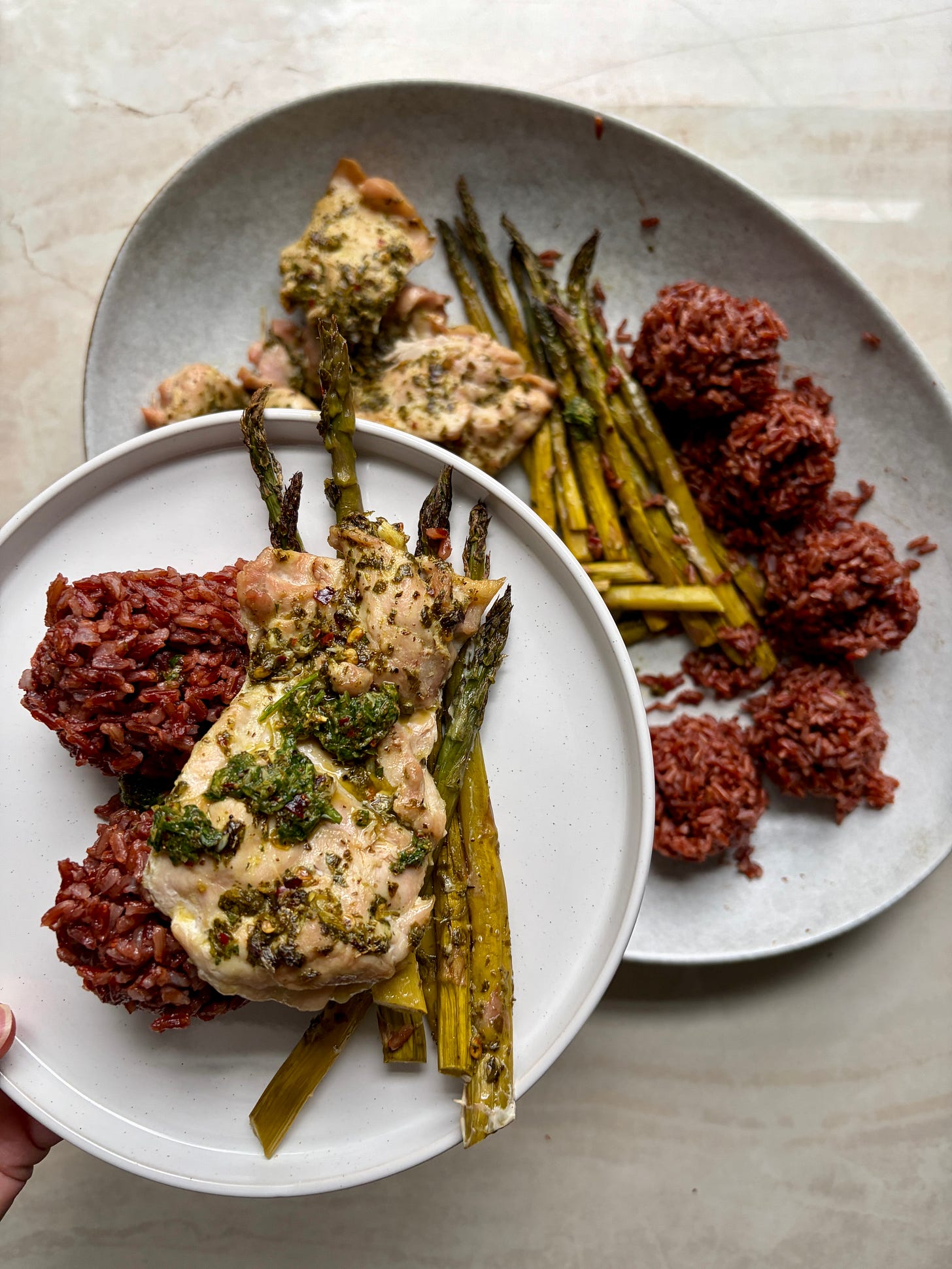 chimichurri chicken thighs roasted asparagus, red rice on a white plate on a marble countertop with 1 plate serving