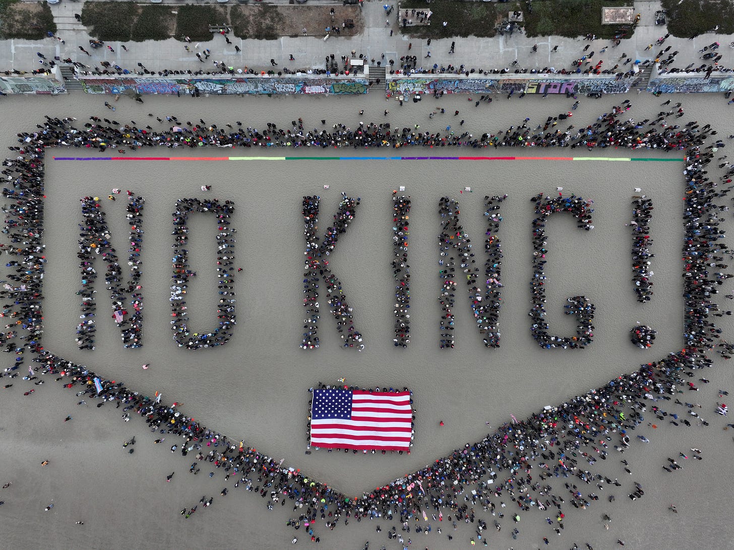 A crowd gathered at Ocean Beach in San Francisco spells out "No King!" when viewed from above.