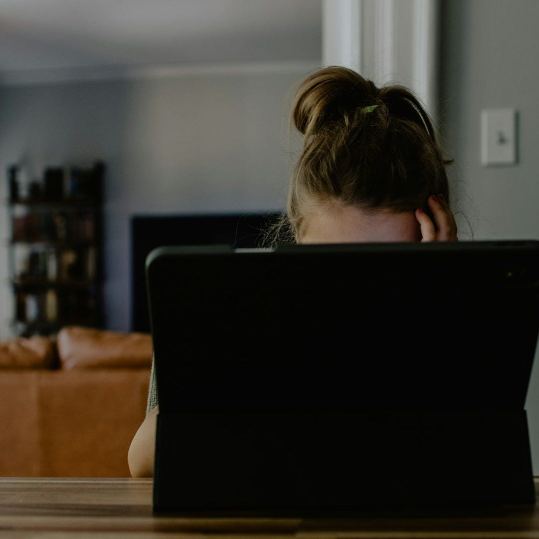 woman in white tank top sitting on chair using black laptop computer