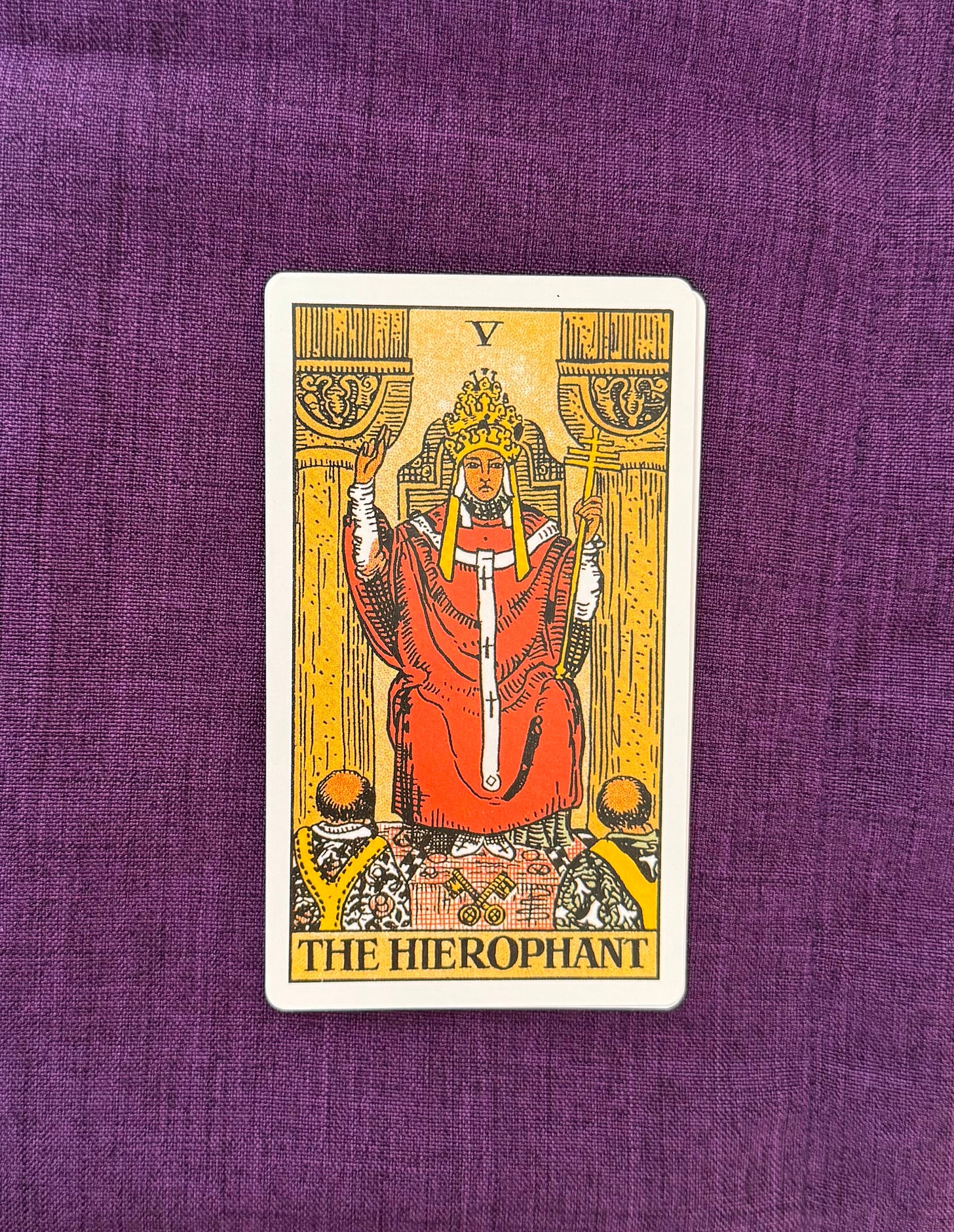 Tarot Card reads “The Hierophant” depicts a pontiff sitting on a throne, wearing a crown, with one hand pointing upwards and the other holding a triple cross. Two monks can be seen at the inferior edges, looking at him. Tarot Card reads “The Hierophant” depicts a pontiff sitting on a throne, wearing a crown, with one hand pointing upwards and the other holding a triple cross. Two monks can be seen at the inferior edges, looking at him.
