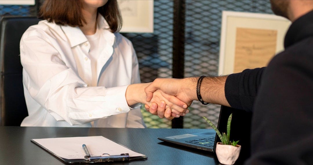 a man and a woman shaking hands in front of a laptop