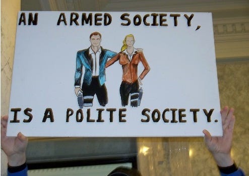 A hand-lettered and illustrated protest sign reading 'An armed society is a polite society.' Drawing in colored marker depicts a white man and woman, both with pistols strapped to their legs. A hand-lettered and illustrated protest sign reading 'An armed society is a polite society.' Drawing in colored marker depicts a white man and woman, both with pistols strapped to their legs.