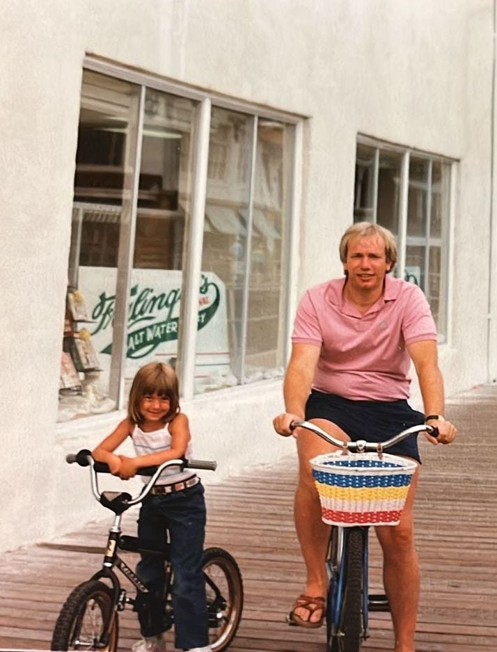 A young girl and her father are posing on their bikes on the Atlantic Ocean boardwalk