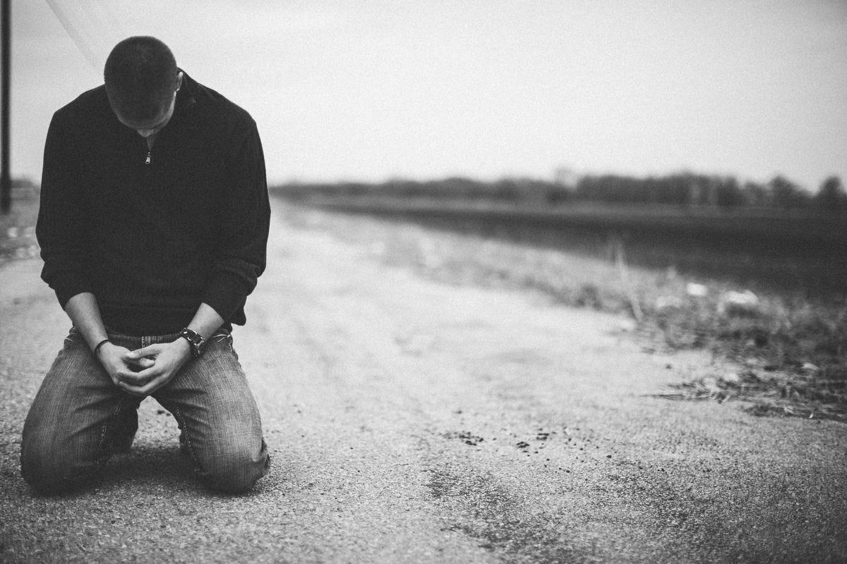 black and white photo of man kneeling with bowed head