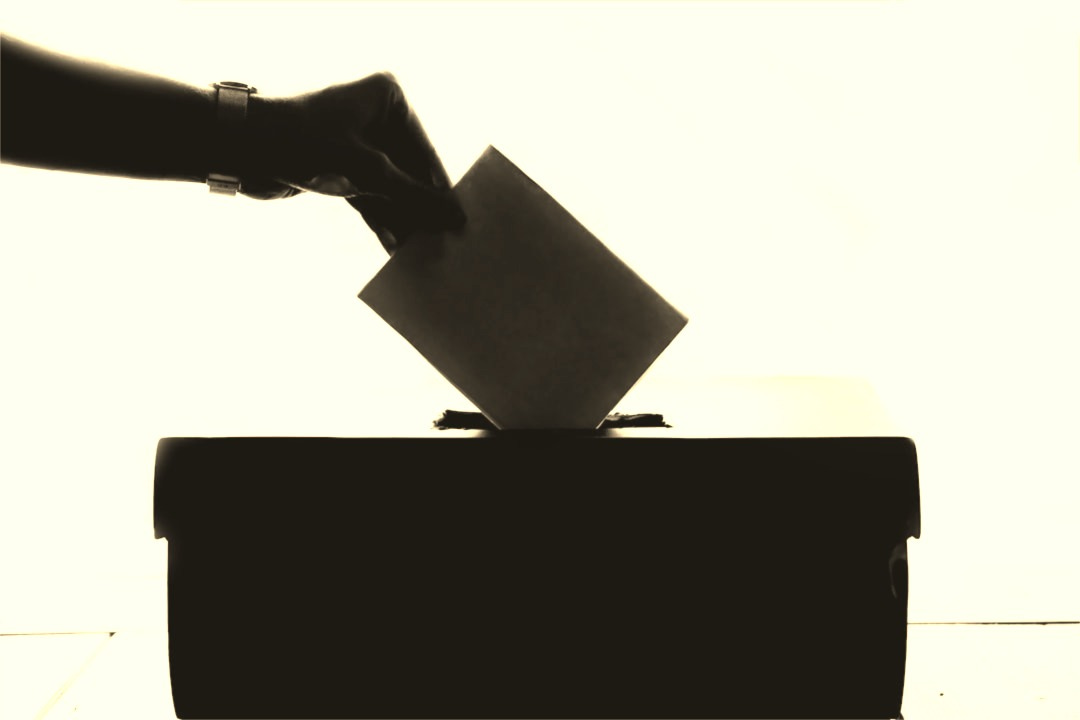 a person is casting a vote into a box