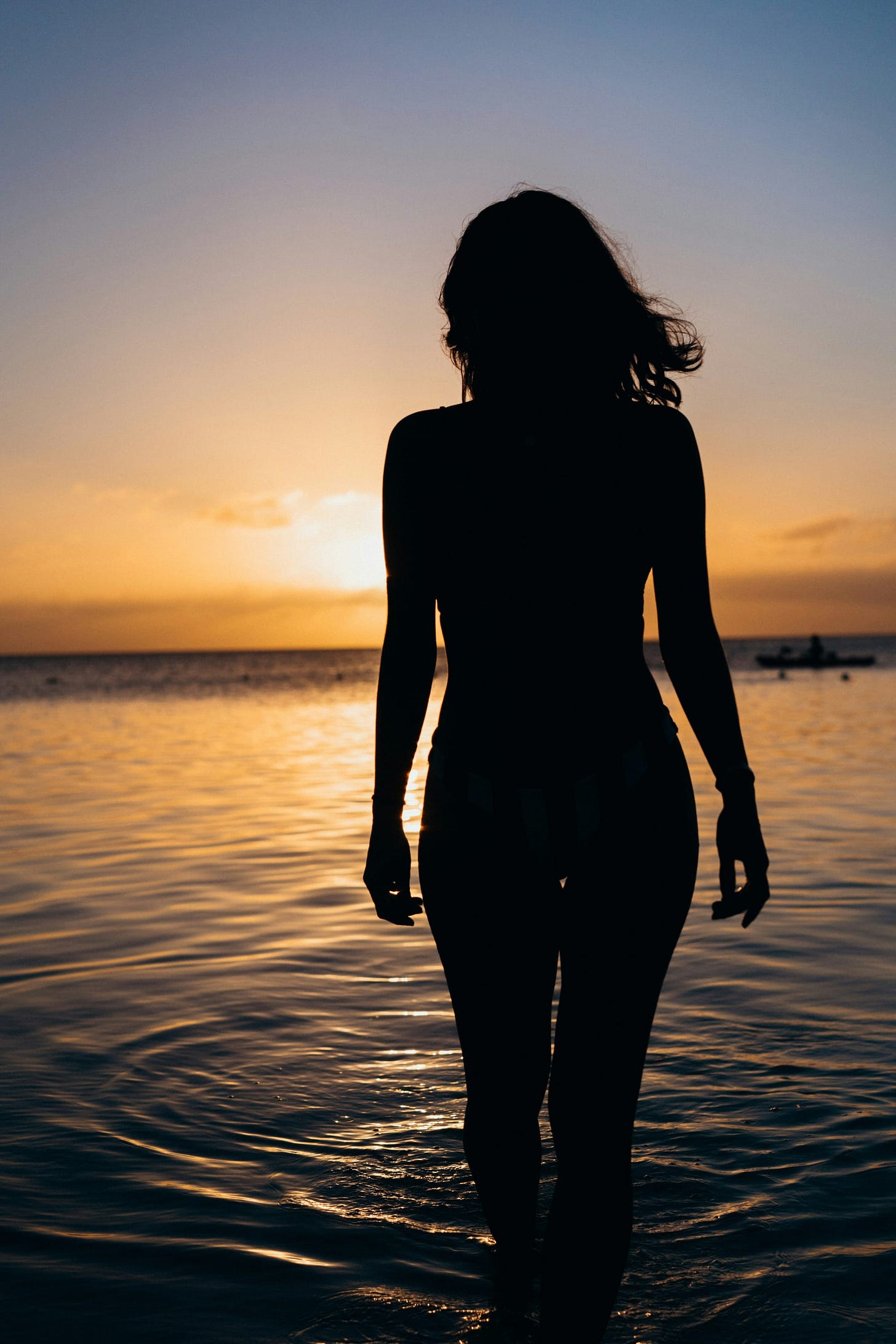 Woman in shadow, facing away and walking in water Woman in shadow, facing away and walking in water