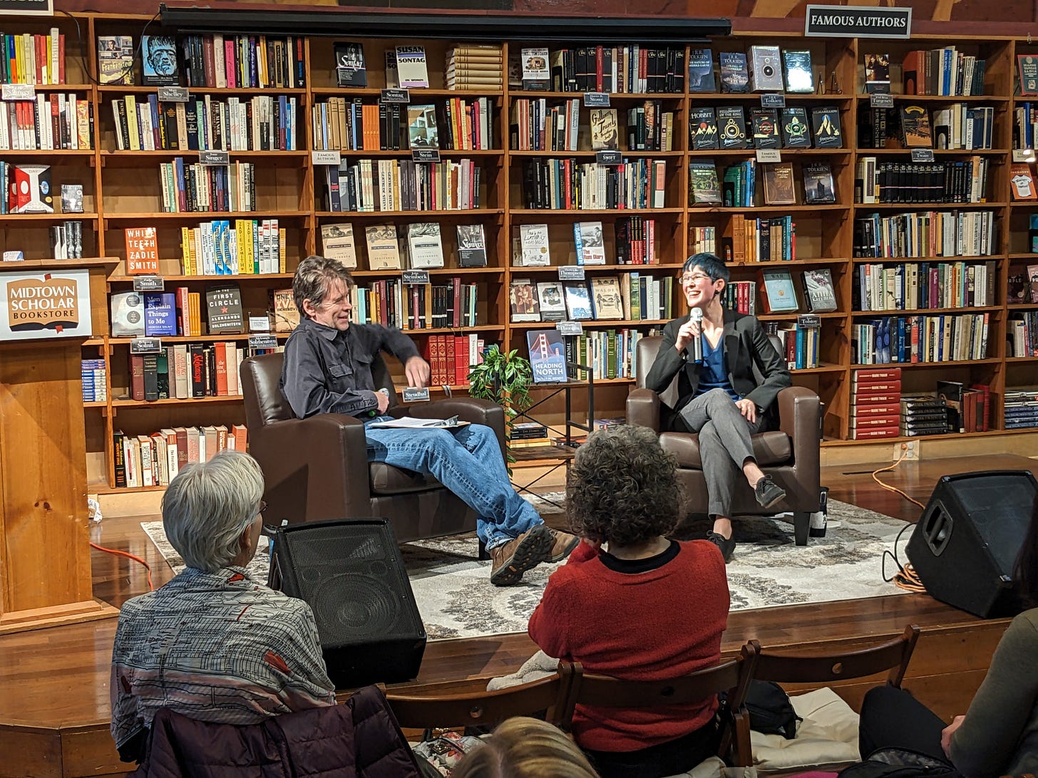 A photo of authors Curtis Smith and Holly M Wendt in conversation at Midtown Scholar bookstore. Both writers are seated in front of a wall of books. A photo of authors Curtis Smith and Holly M Wendt in conversation at Midtown Scholar bookstore. Both writers are seated in front of a wall of books.