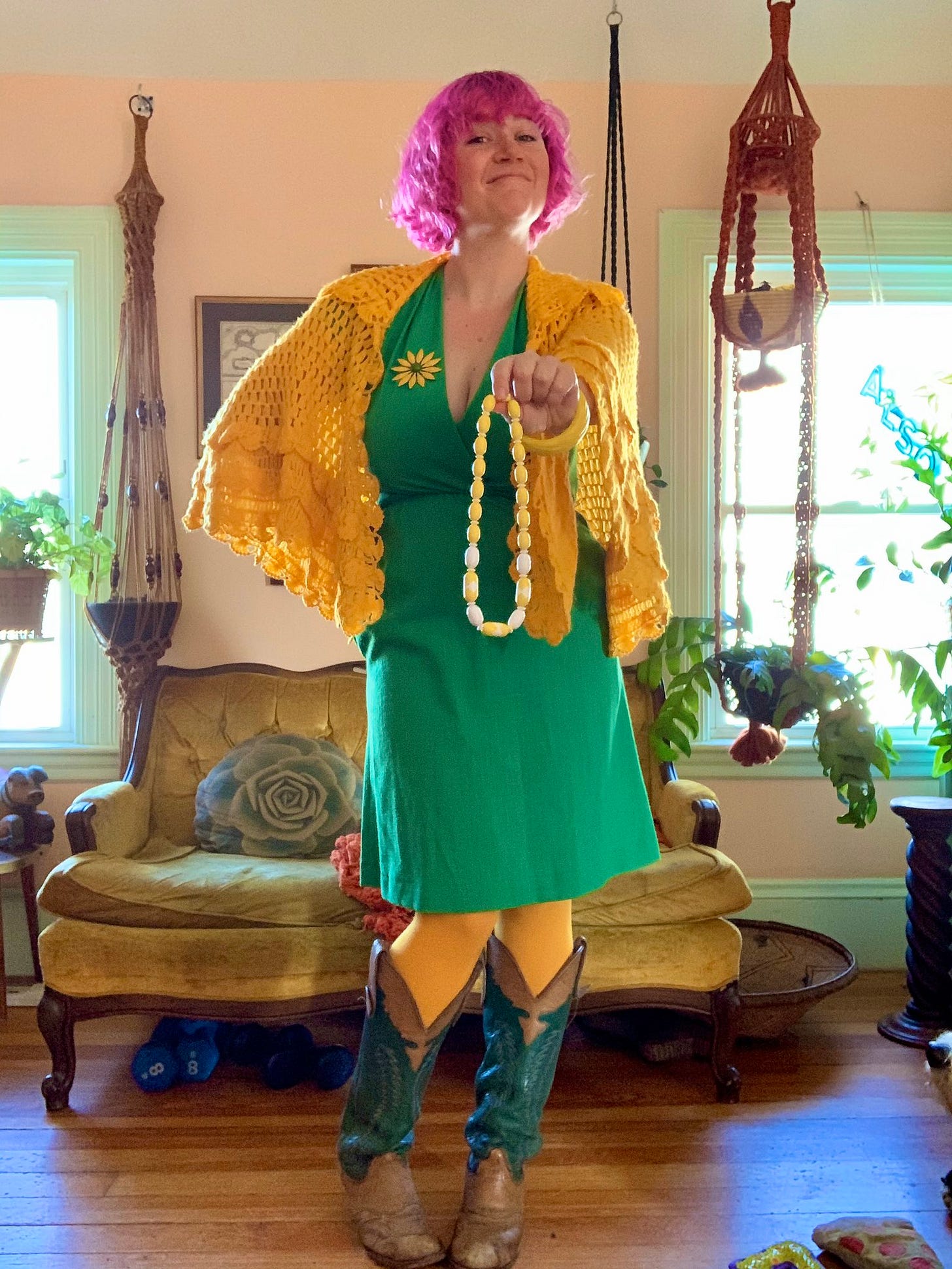 Woman with magenta hair wearing colorful clothes and holding out a necklace