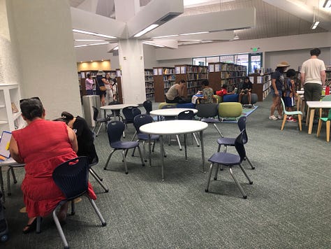 People in library borrowing books, browsing, reading 