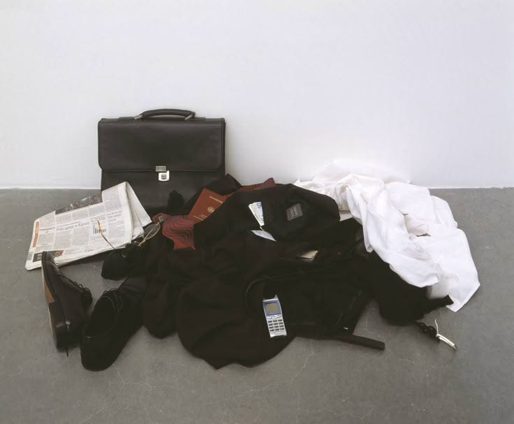 This may contain: an assortment of clothing and accessories sitting on the floor next to a briefcase with papers