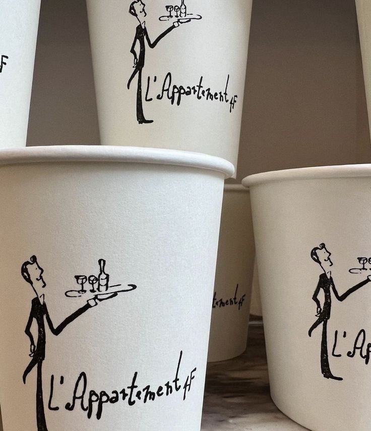 This may contain: four white cups with black writing on them and one has a waiter holding a tray