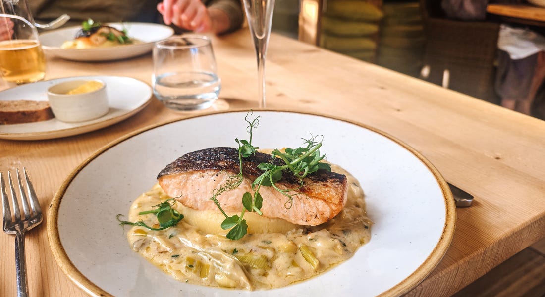 A round plate with a fillet of salmon and creamed leeks on a wooden table A round plate with a fillet of salmon and creamed leeks on a wooden table