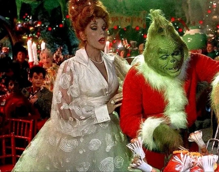 This may contain: two people dressed in costumes standing next to each other at a christmas party with many people