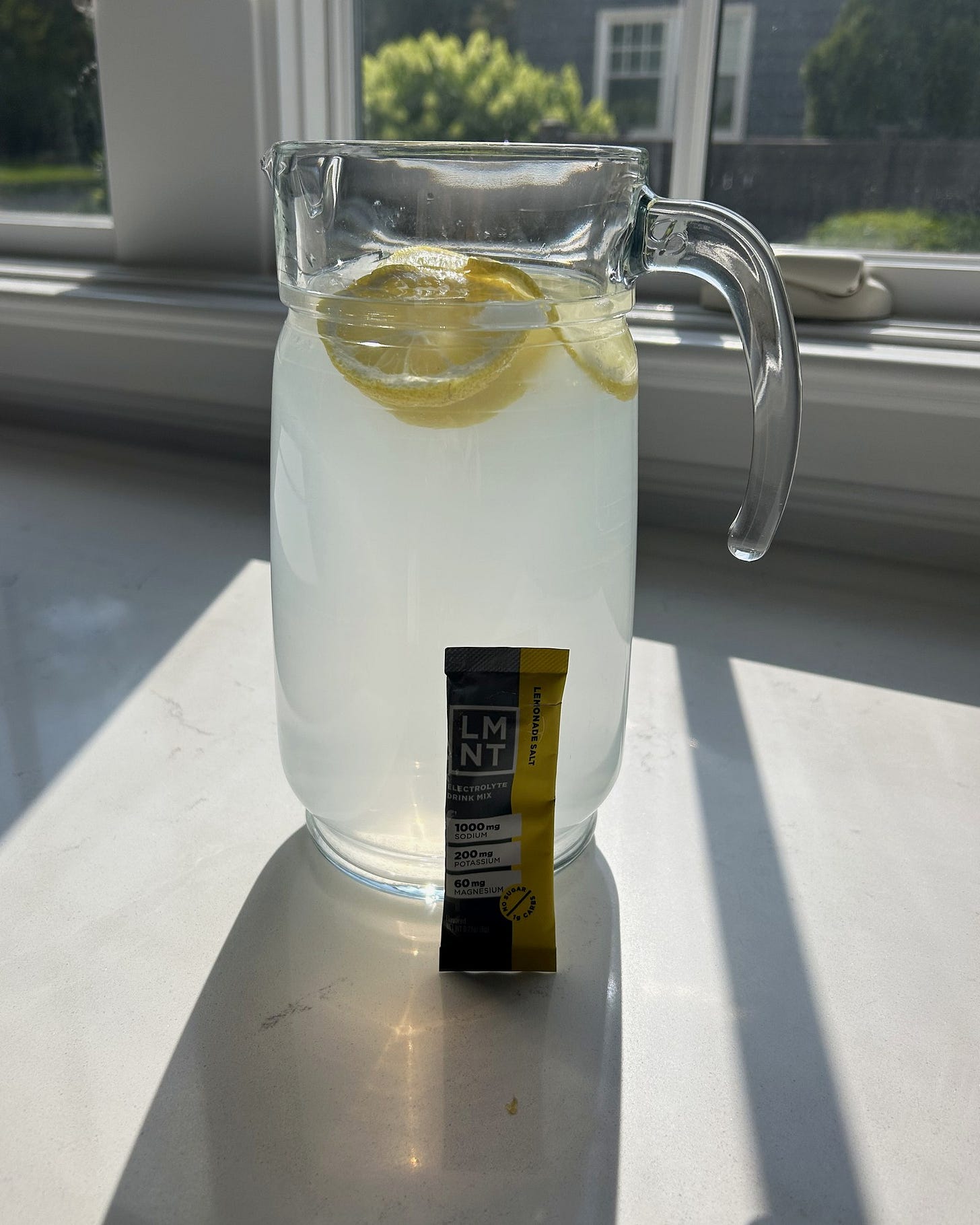 A glass pitcher of LMNT lemonade electrolyte drink on a kitchen counter. A glass pitcher of LMNT lemonade electrolyte drink on a kitchen counter.