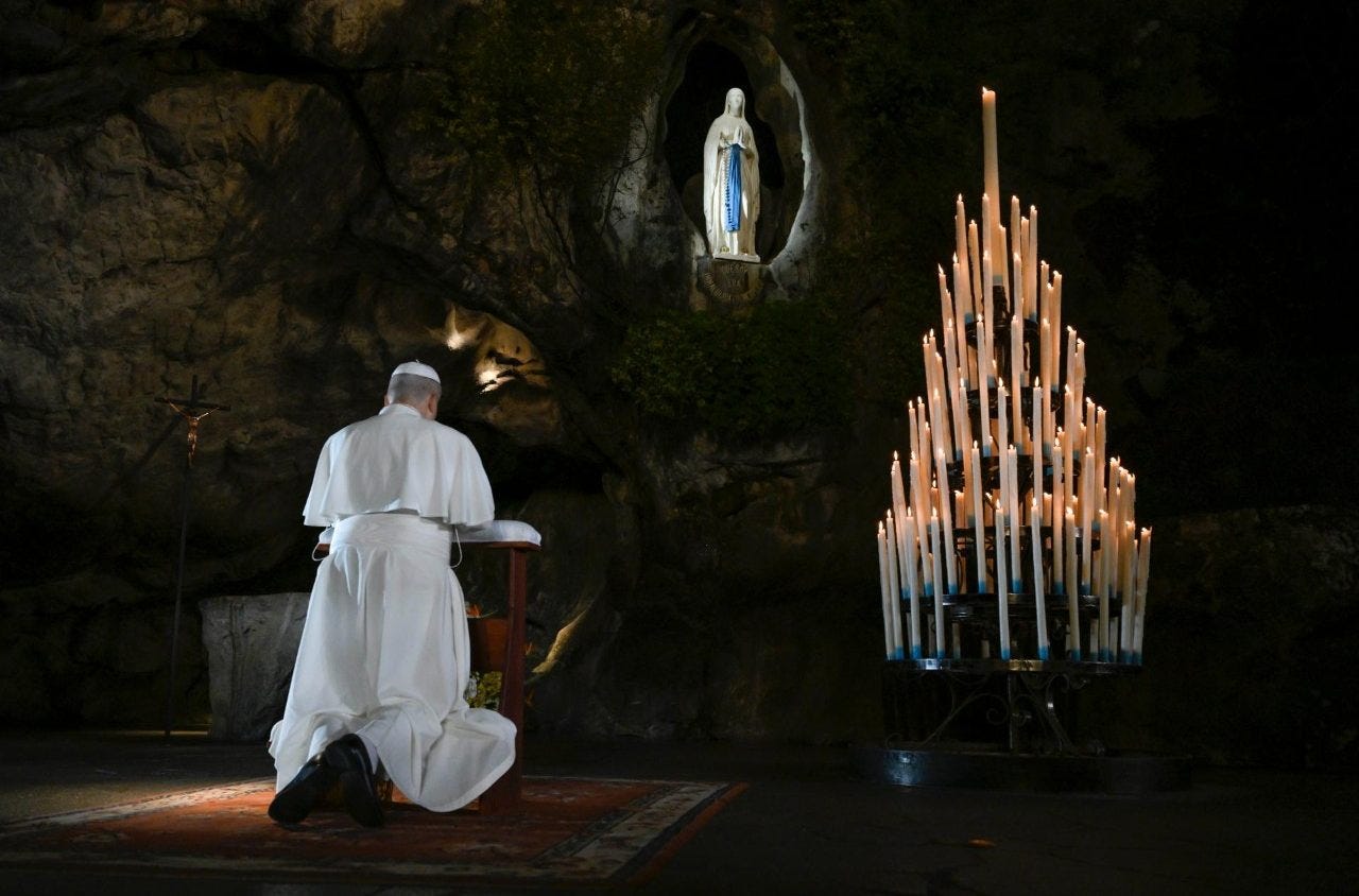 Pope Leo XIV kneels in prayer at the Grotto of Massabielle in Lourdes
