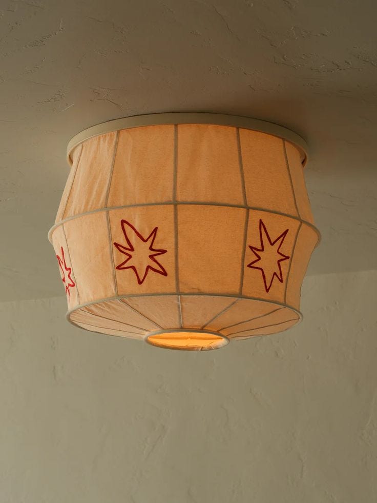 This may contain: a lamp hanging from the ceiling with red stars painted on it's lampshade This may contain: a lamp hanging from the ceiling with red stars painted on it's lampshade