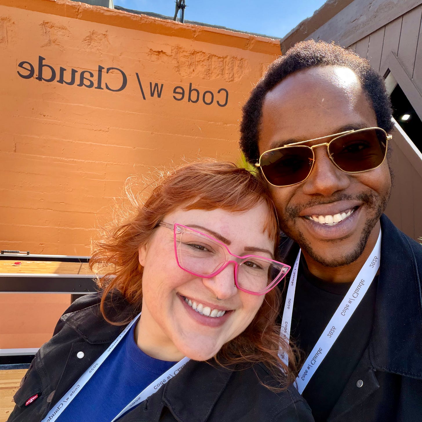 Two people smiling together at Code with Claude 2026 in San Francisco, wearing conference badges in front of an orange “Code w/ Claude” wall. Two people smiling together at Code with Claude 2026 in San Francisco, wearing conference badges in front of an orange “Code w/ Claude” wall.