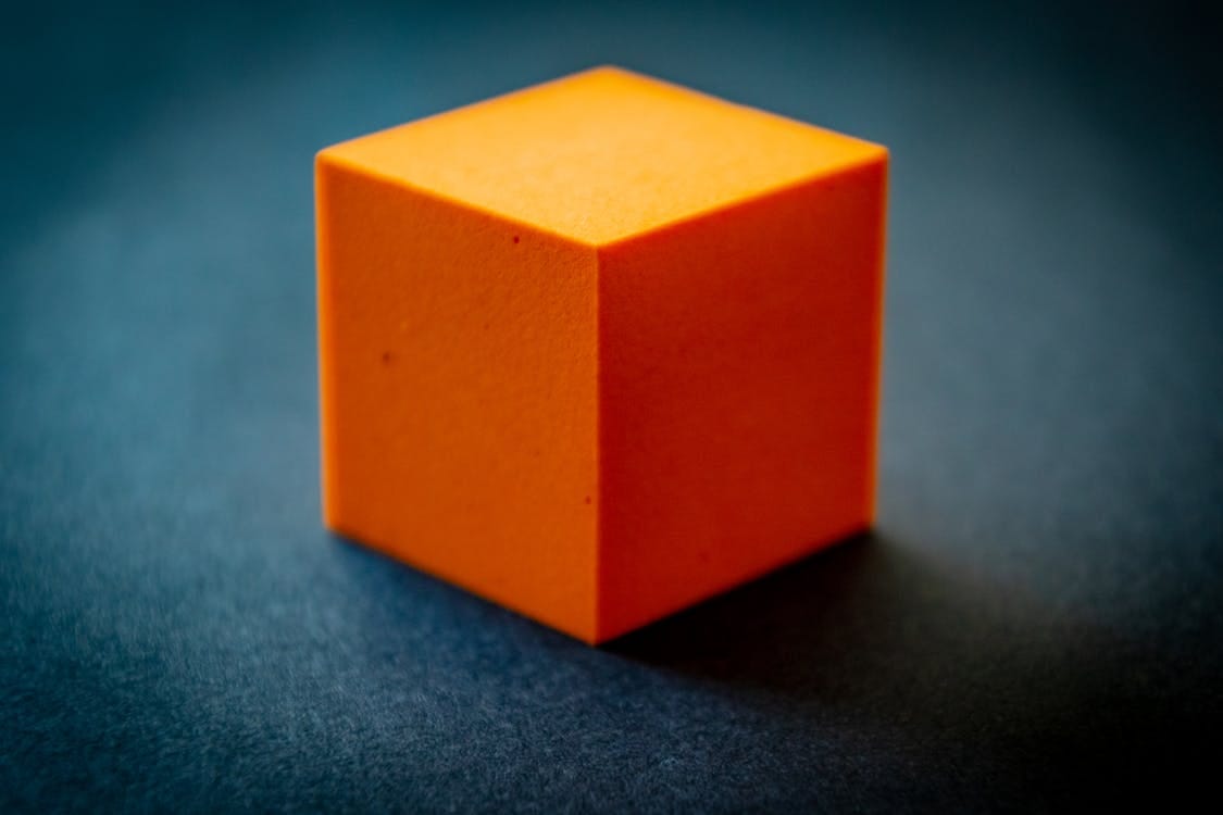 Free Close-up of an orange foam cube on a dark surface, highlighting its texture and color contrast. Stock Photo