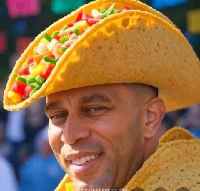 A person wearing a large, taco-shaped hat filled with colorful toppings including lettuce, tomatoes, and cheese. The hat resembles a hard-shell taco, with visible details like the shell texture and vibrant ingredients. The person is also wearing a matching taco-themed outfit, featuring a textured, yellow fabric resembling a taco shell.