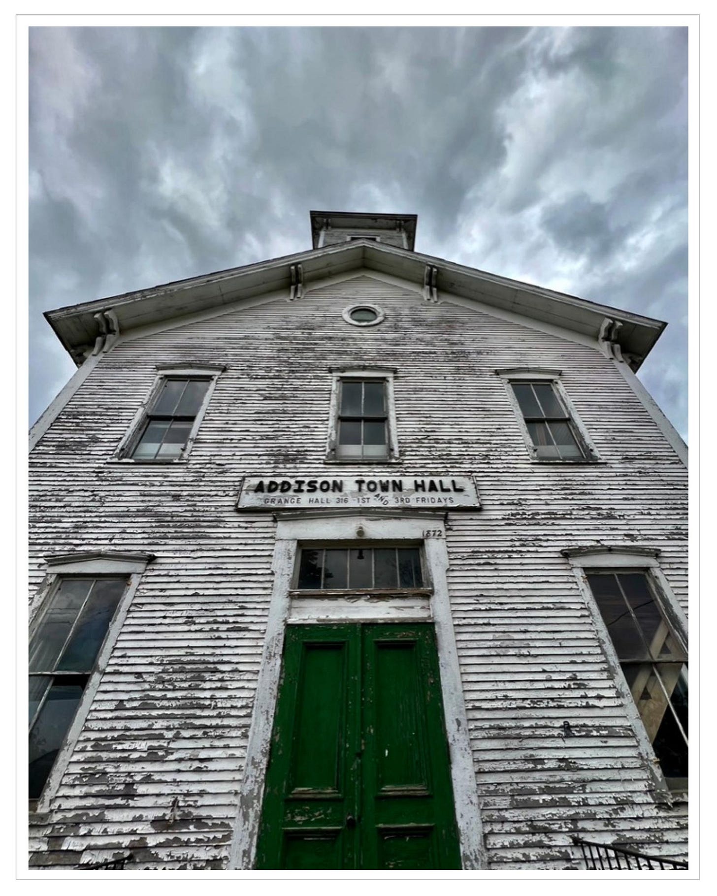 Historic white clapboard building: "Historic Town Hall," striations of dark grey clouds