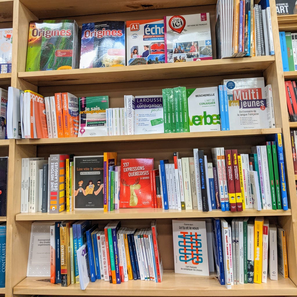 A bookshelf containing linguistics and reference books in French, including 337 Expressions Quebecoises, Le tu et le vous, and Une Histoire des Languages.