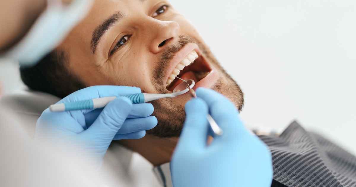 man sitting in the dentist chair while getting his teeth checked