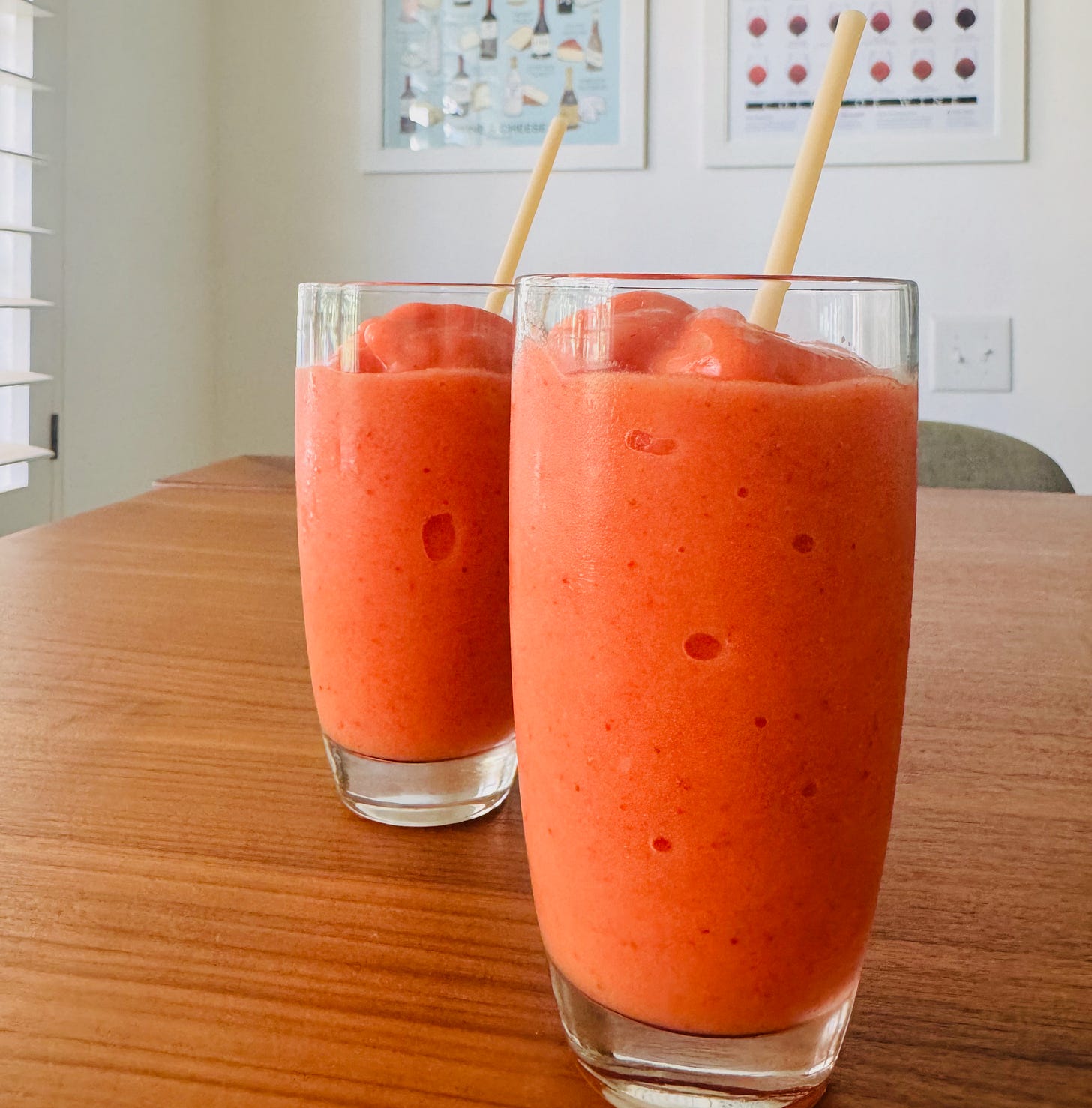 Two glasses of Surf City Sunrise Smoothie, with straws, ready to drink, placed on a table lit bu the desert sun. Two glasses of Surf City Sunrise Smoothie, with straws, ready to drink, placed on a table lit bu the desert sun.