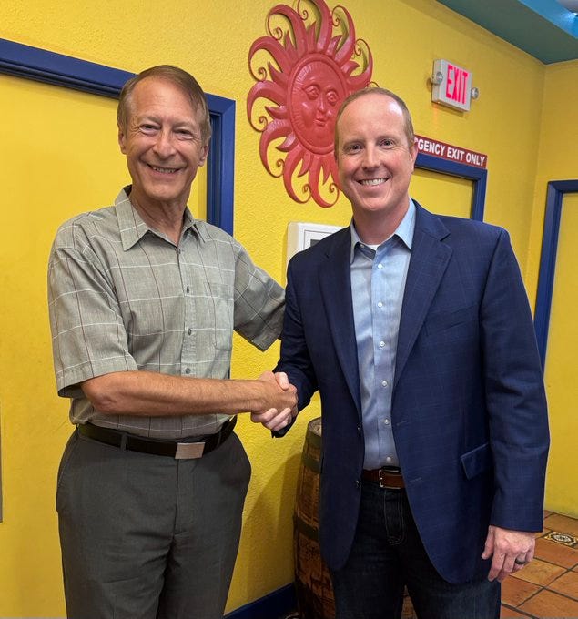 First image depicts two men in a brightly lit room with yellow walls and blue trim shaking hands smiling at each other. The older man on the left wears a checkered short-sleeve shirt and khaki pants while the younger man on the right wears a light blue dress shirt navy suit jacket and dark pants. A large red sun decoration hangs on the wall behind them along with an exit sign and a wooden barrel nearby. Second image is a blue and red infographic titled ECON 101 listing principles such as People act purposefully Trade creates value Entrepreneurship drives growth Nothing is free Voluntary exchange works best Price signals matter Opportunity costs are real Inflation comes from the Fed Trade beats war Socialism fails Profits and losses matter Let markets work No Keynesian multiplier signed by Vance Ginn.