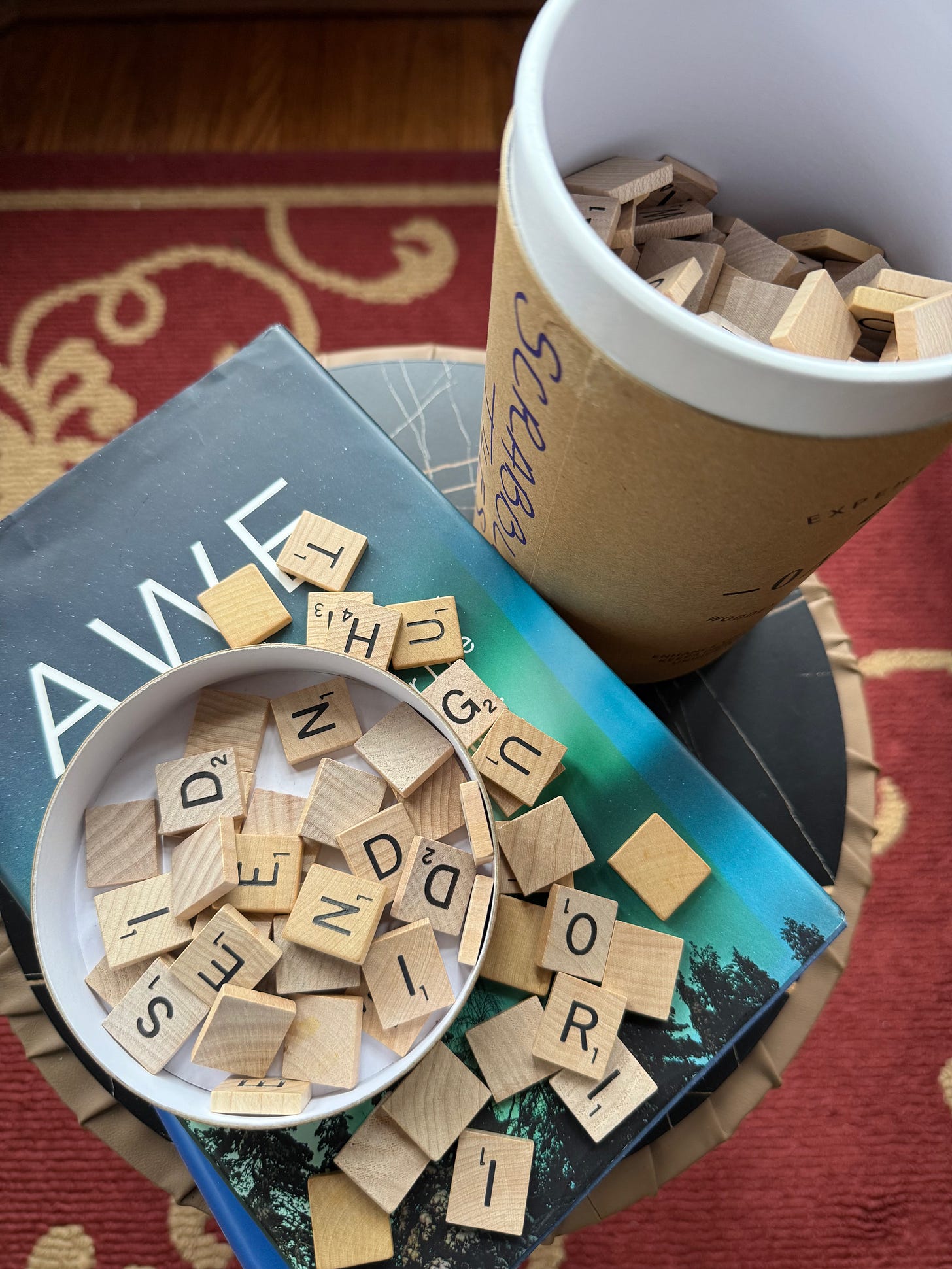 Scrabble letter tiles on top of a book and in a container Scrabble letter tiles on top of a book and in a container