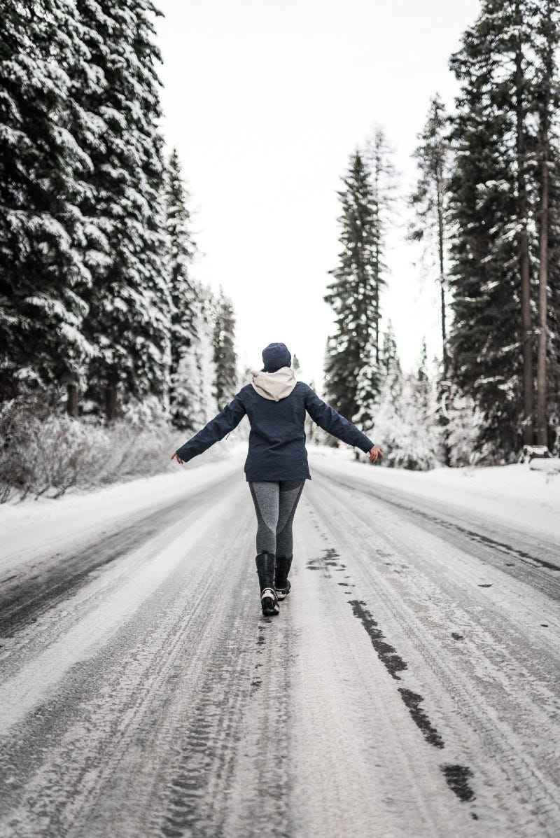 person in blue jacket and pants walking on snowy road during daytime