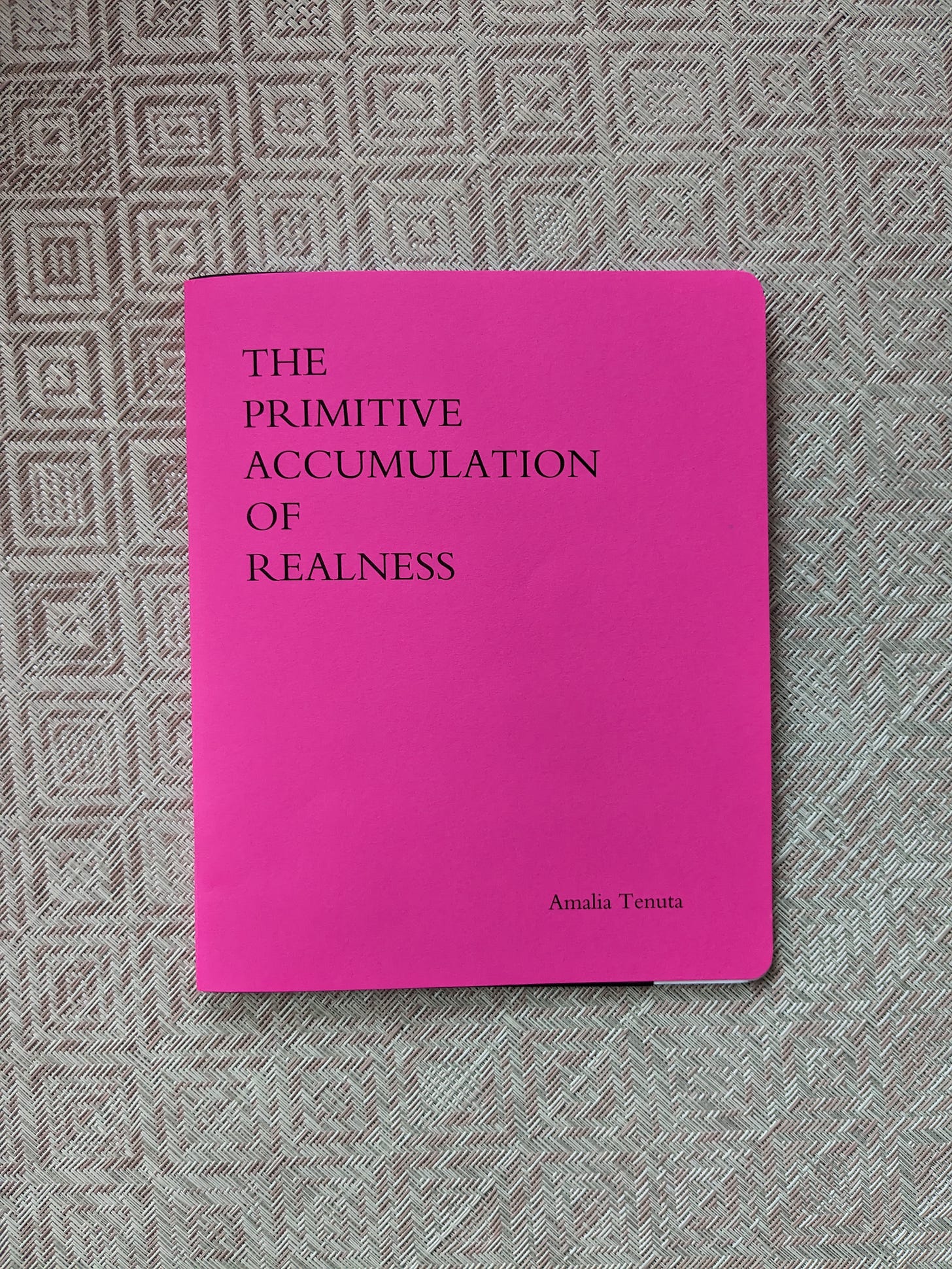 Photo of neon pink book on a pale pink mat.