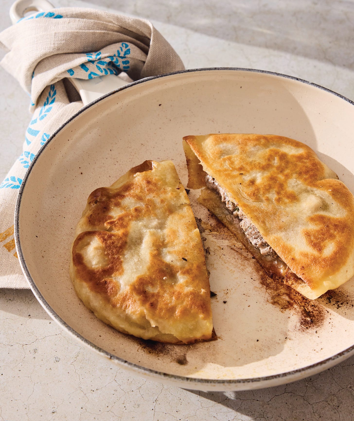 Arayes recipe in a pan with a towel around the handle.