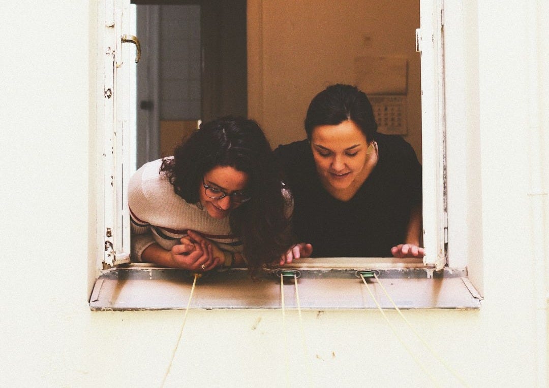 two woman looking through window two woman looking through window