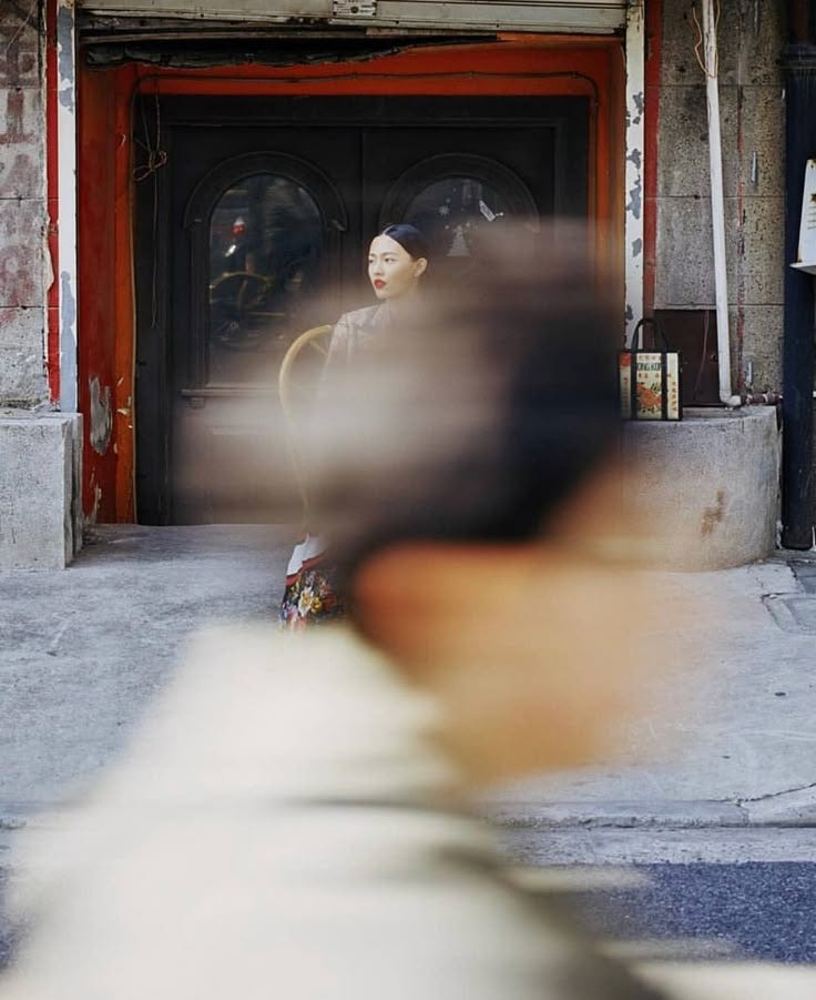 This may contain: a blurry photo of a woman sitting in front of a building with a red door