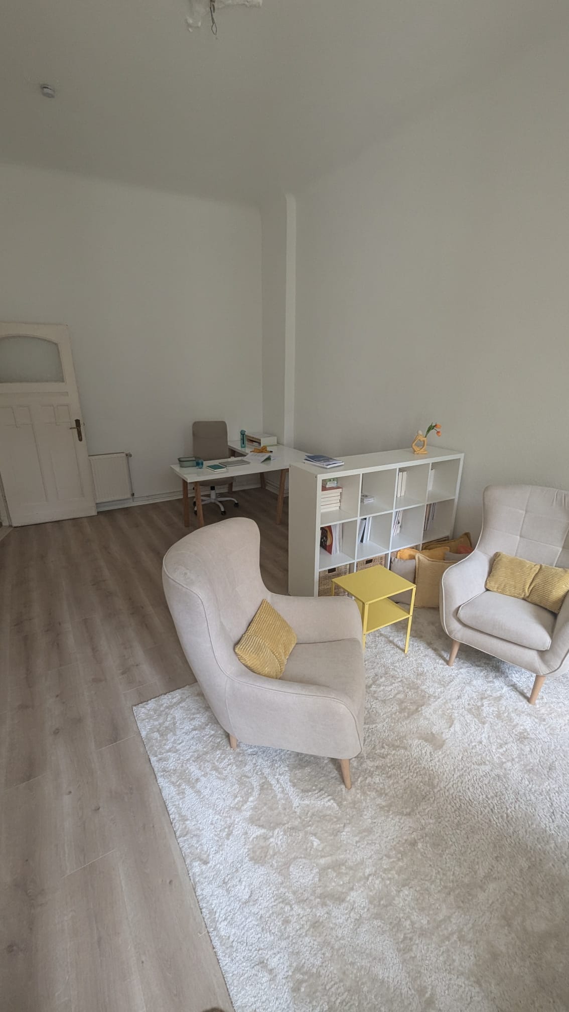 Mein Sprechzimmer mit zwei Sesseln, einem Regal und einem Schreibtisch.