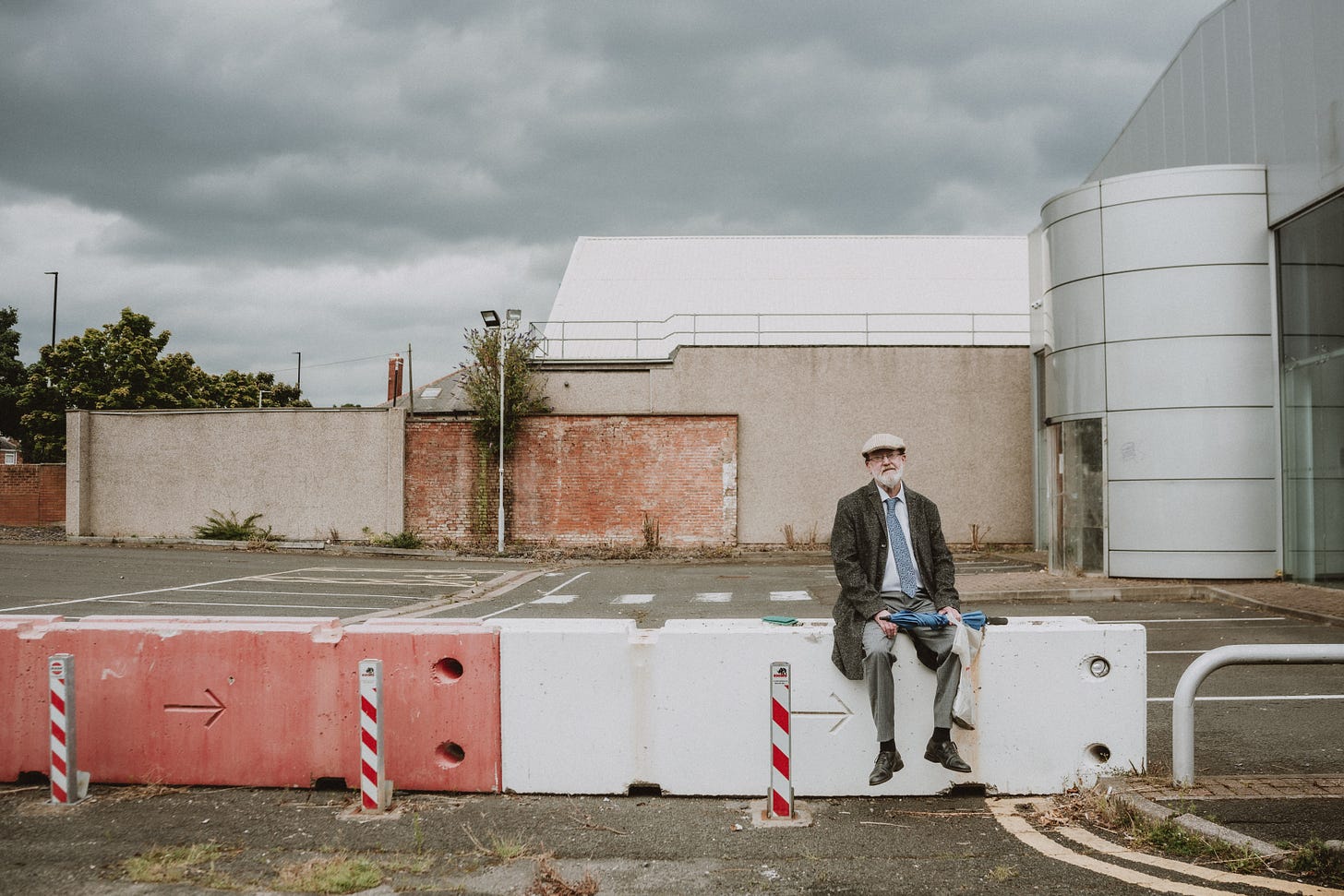 A photo of Nev Clay, sitting on the end of a red and white concrete barrier.