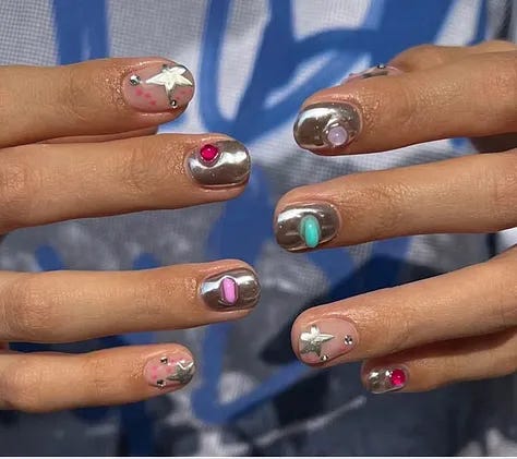 A close up shot of a gem stone manicure that is bright and fun