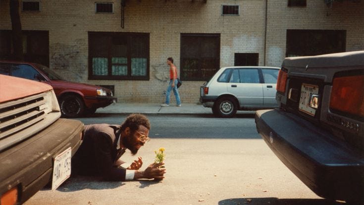 This may contain: a man laying on the ground next to parked cars