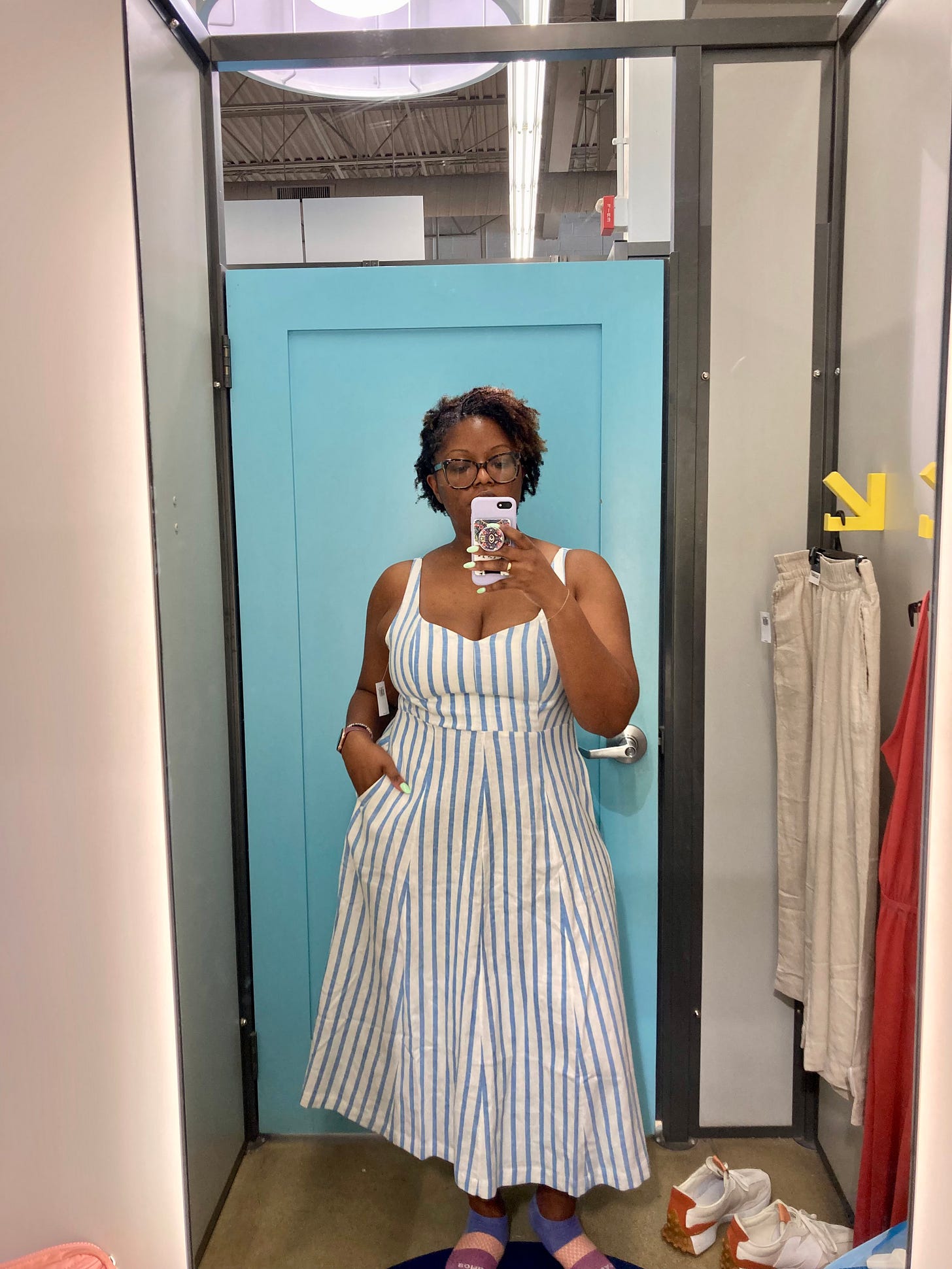 Picture of a Black woman wearing a blue and white striped A-line dress in an Old Navy dressing room