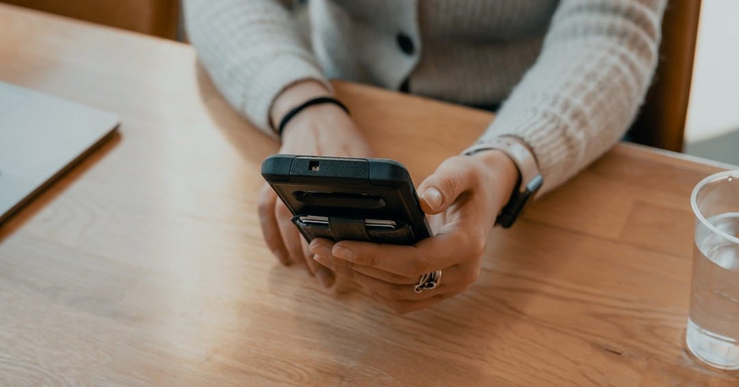 woman in white sweater holding black smartphone